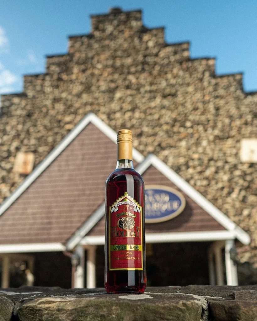 Holiday Spiced Wine bottle displayed outdoors on a stone wall in front of Grand Salon