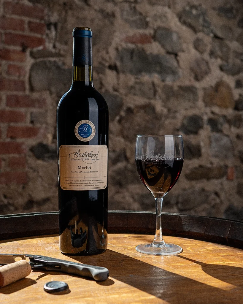 Red wine bottle on rustic barrel table inside historic tasting room